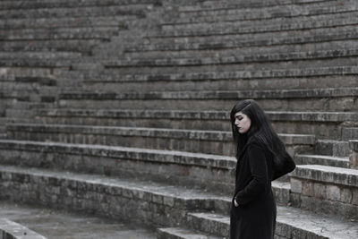 Portrait of woman standing against staircase