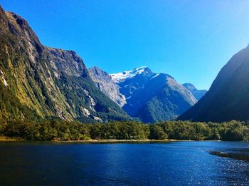Scenic view of lake and mountains against clear blue sky