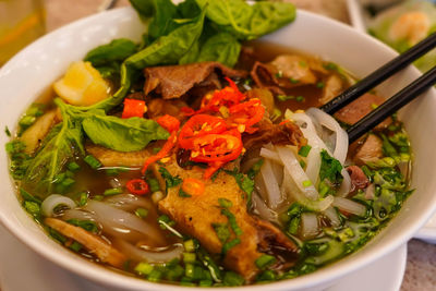 Pho bo or vietnamese soup with beef and meat balls served in a white bowl at the restaurant. 