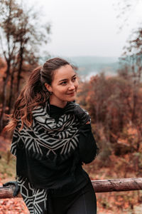 Young woman looking away while standing in forest
