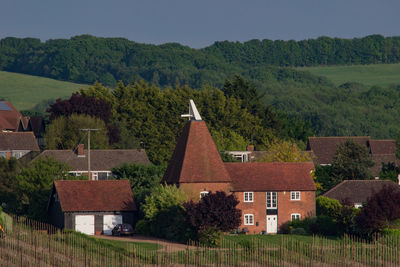 Houses on field by buildings against sky