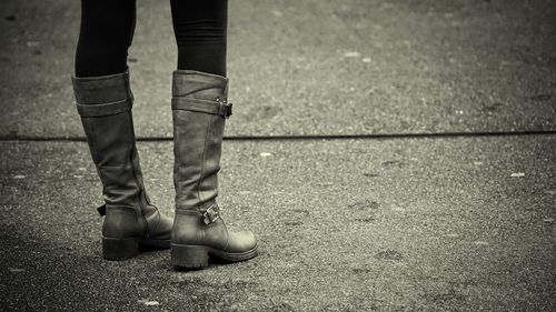 Low section of woman wearing boots on footpath