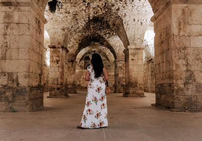 Rear view of female tourist standing in large underground room of an ancient roman palace in split