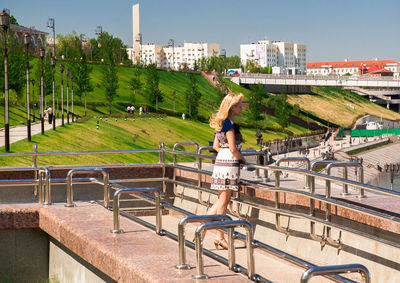 Woman on railing in city against sky