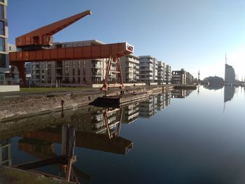 Reflection of buildings in lake against clear sky