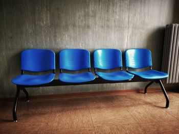 Empty blue chairs against wall