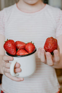 Midsection of woman holding strawberries