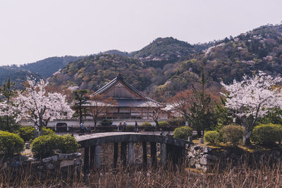 Built structure by trees and plants against sky