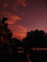 Cars on street against sky at sunset