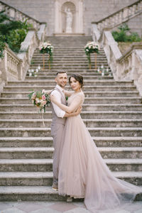 Portrait of bride and bridegroom standing against wall