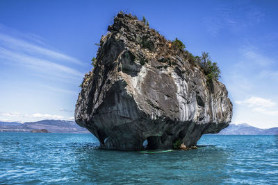 Rock formation in sea against blue sky