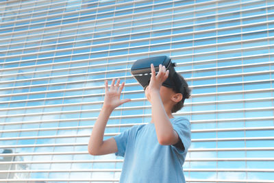 Boy wearing virtual reality simulator against building