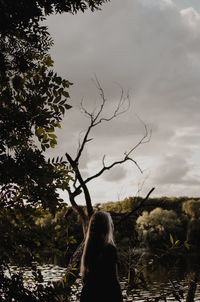 Woman standing by tree on field against sky