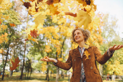 Woman playing with leaves at park during autumn