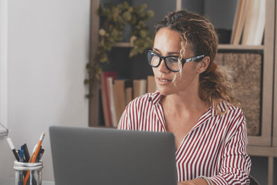 Young woman using laptop while sitting on sofa at home