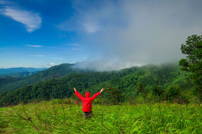 Person jumping on mountain against sky