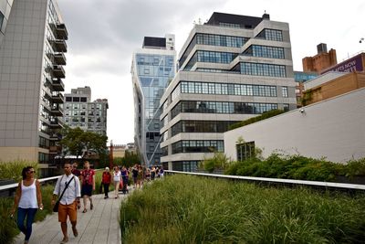 People walking on steps in city against sky