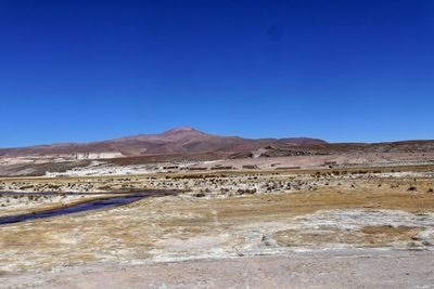 Scenic view of arid landscape against clear blue sky