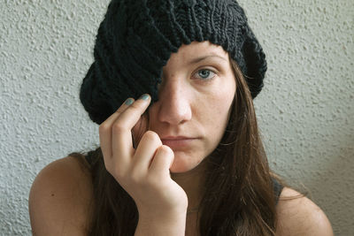 Young woman wearing knit hat against wall at home