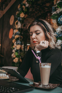 Young woman looking away while sitting on table