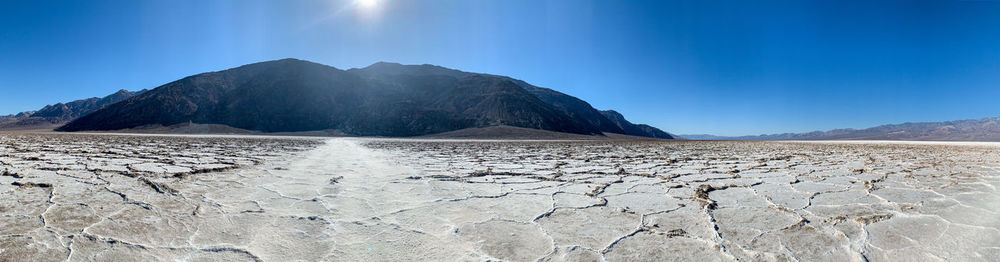 Scenic view of arid landscape against blue sky