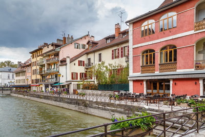 Houses by river in town against sky