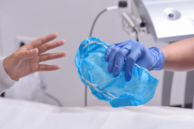 Cropped hand of nurse giving surgical cap to patient in hospital