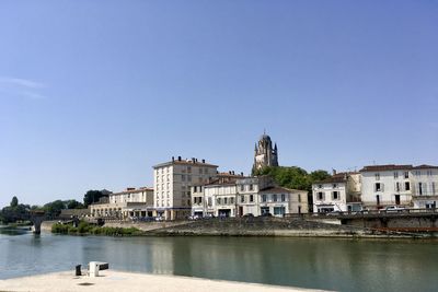 River by buildings against clear blue sky