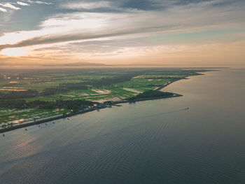 Aerial view of city by sea against sky