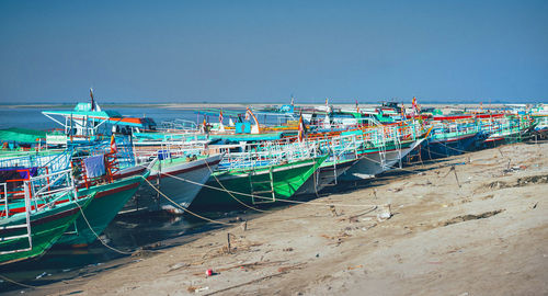 Fishing boats moored at harbor against clear sky