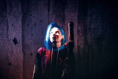 Portrait of young woman standing against wall