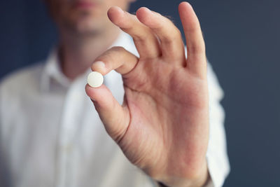 Midsection of man holding pill