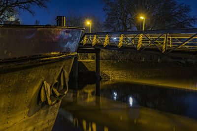 Boat in canal by footbridge at night