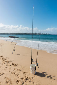 High angle view of fishing rods at sea shore against sky