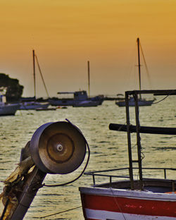 Sailboats moored on sea against sky during sunset