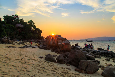 Rocks on beach against sky during sunset