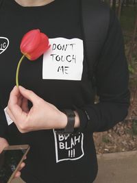 Midsection of man holding flower with text