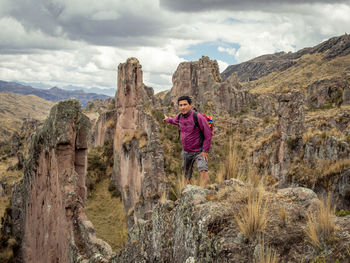 Full length of man standing on rock against sky