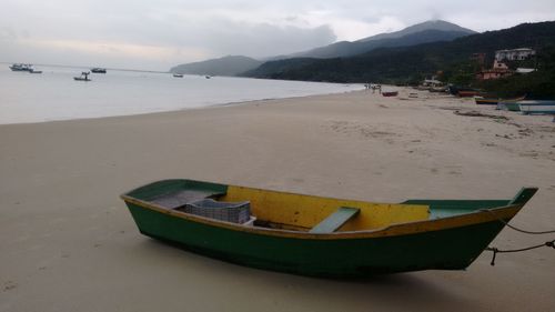 Boat moored on beach against sky