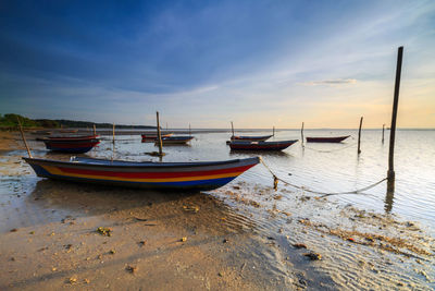 Sailboats moored on sea against sky during sunset