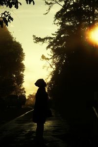 Silhouette woman walking on road against sky during sunset