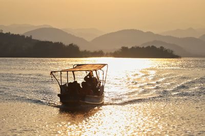 Boat in sea against sky during sunset