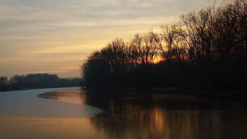 Silhouette trees by lake against sky during sunset