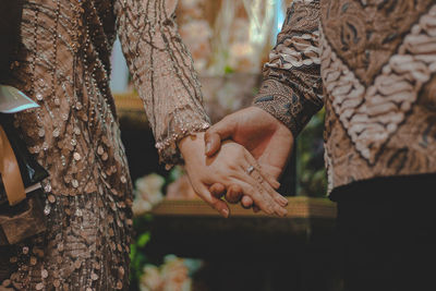 Midsection of couple holding hands outdoors