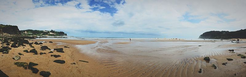 Scenic view of beach against cloudy sky