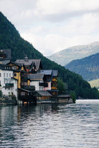 Houses by river against mountains and sky in city