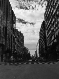 View of empty road in city against cloudy sky