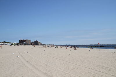 Group of people on beach against sky in city
