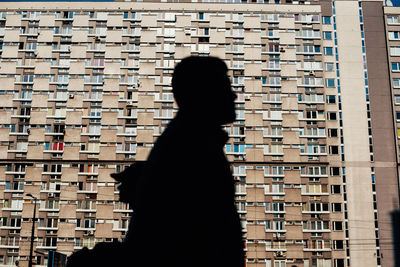 Rear view of silhouette woman standing against building