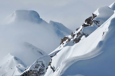 Snow covered high mountains, fog and clouds raising from above. alps, austria